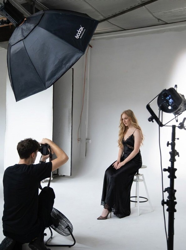 A studio photo session with lighting set around a client in an evening gown