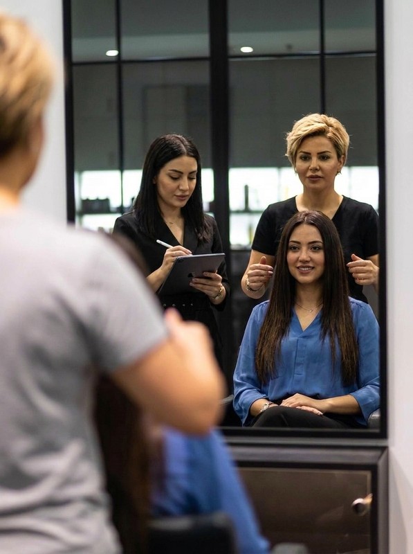 Stylists consulting with a client at the mirror before her hair extensions
